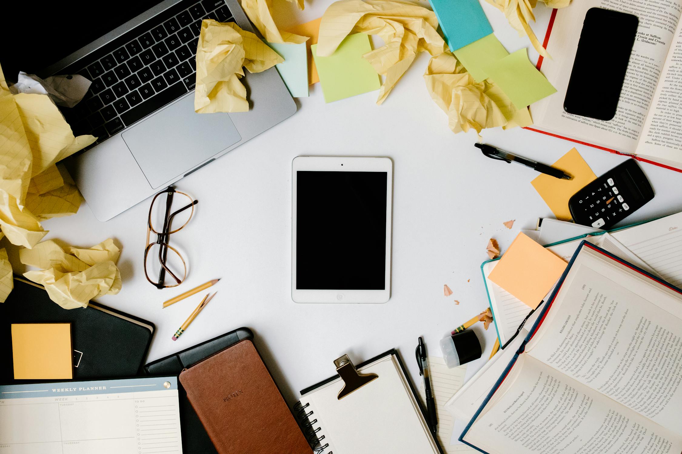 Chaotic creative business desk with scattered papers, post-its, and office supplies showing poor business organization