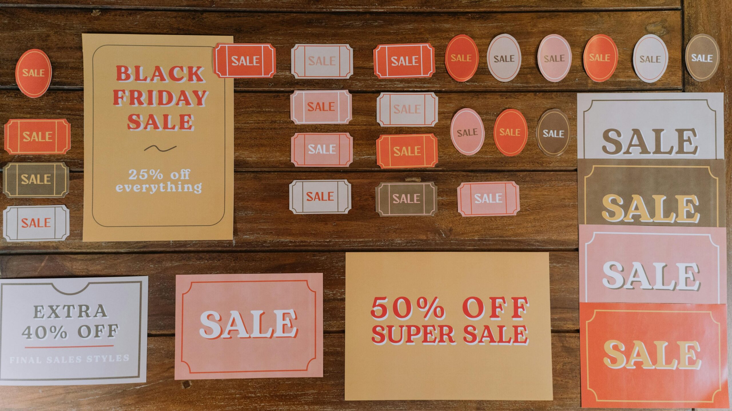 Multiple sale and discount signs on wooden background showing price-based competition vs value based pricing strategy