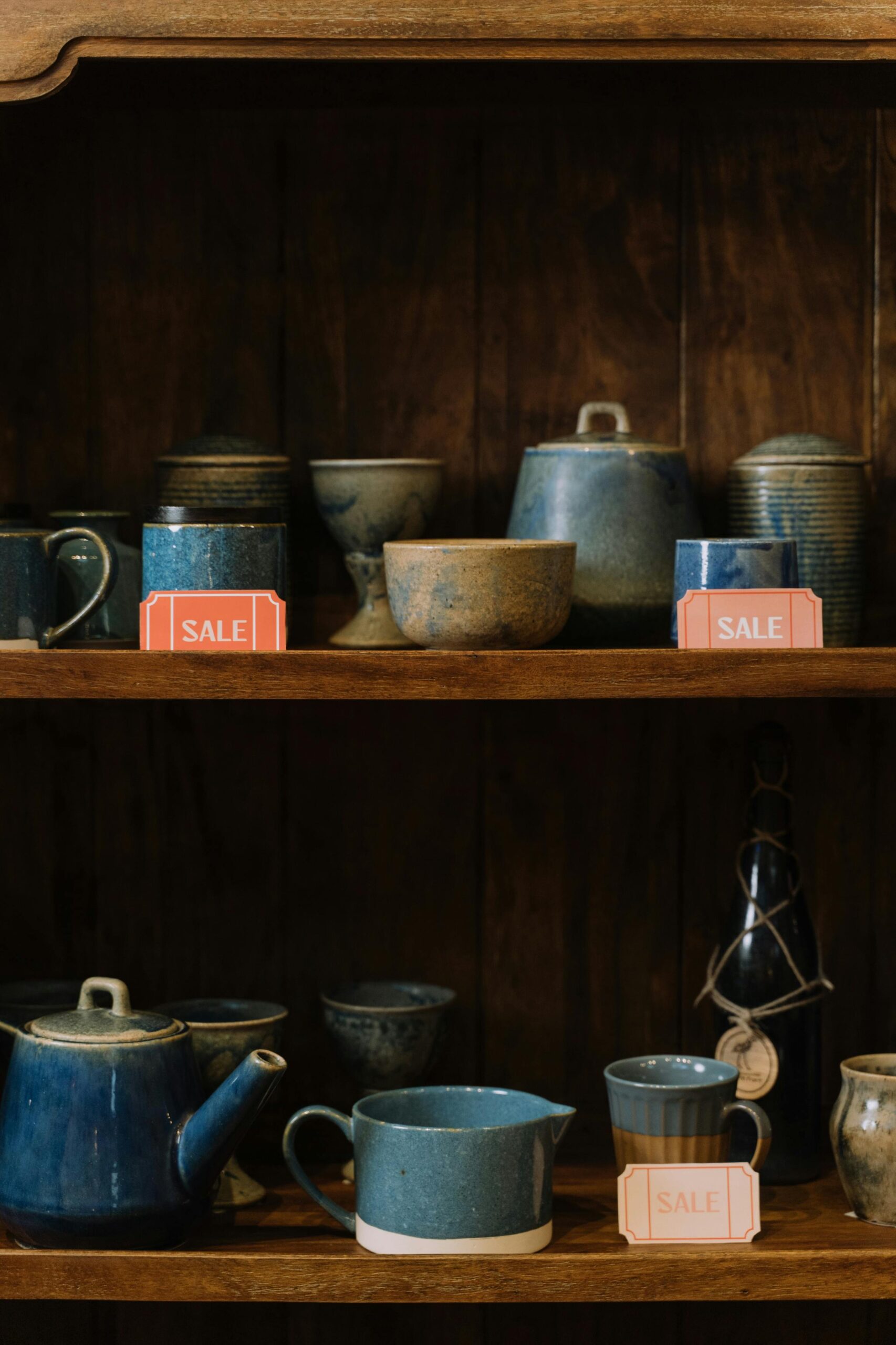 Handmade pottery and ceramics on wooden shelves with sale tags, representing creative work that needs protection from copycats
