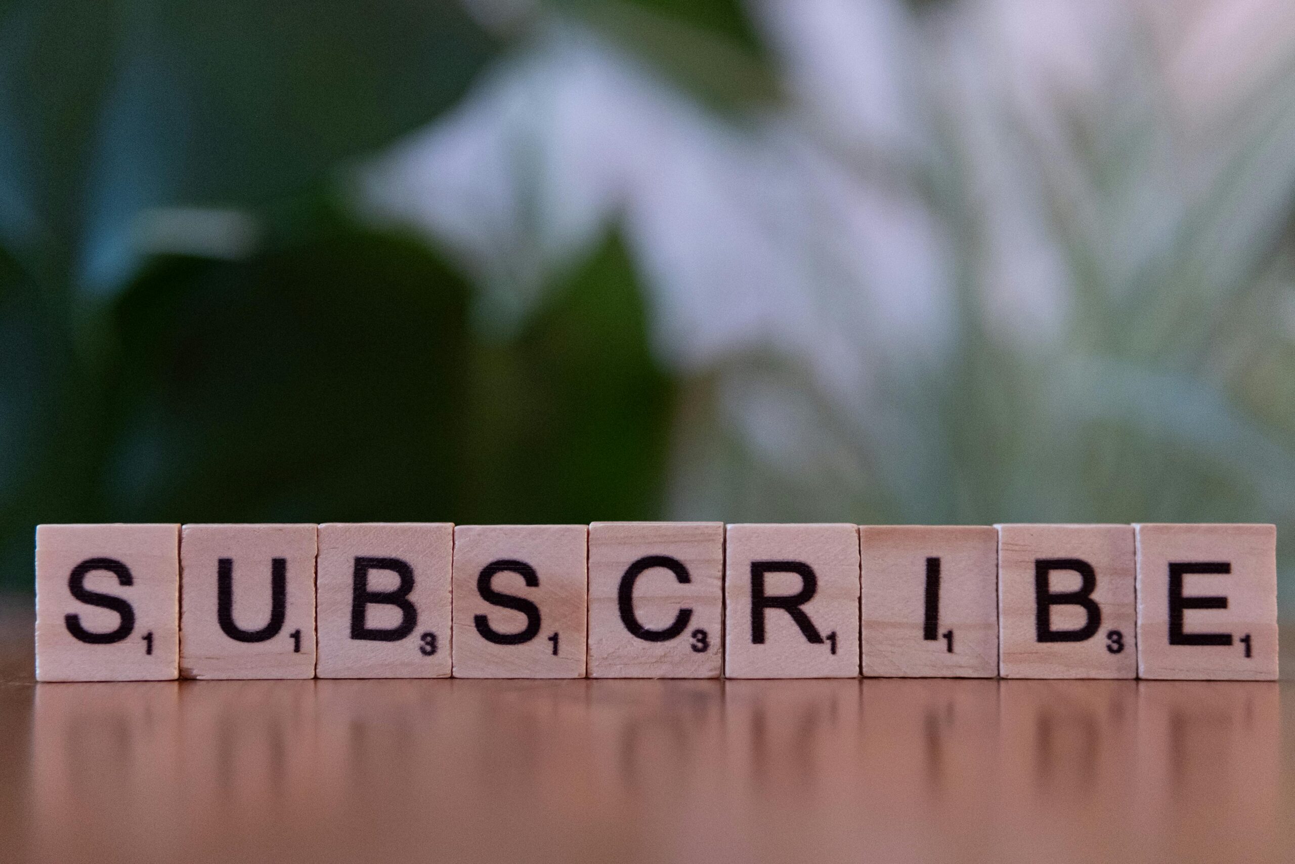 Wooden scrabble tiles spelling out "SUBSCRIBE" representing subscription business model for creative entrepreneurs